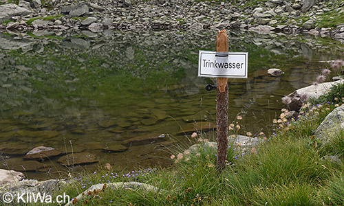 Symbolbild Trinkwasser: Das Schild weist darauf hin, dass aus diesem Bergsee in den Schweizer Alpen Trinkwasser für Mensch und Vieh bezogen wird.
